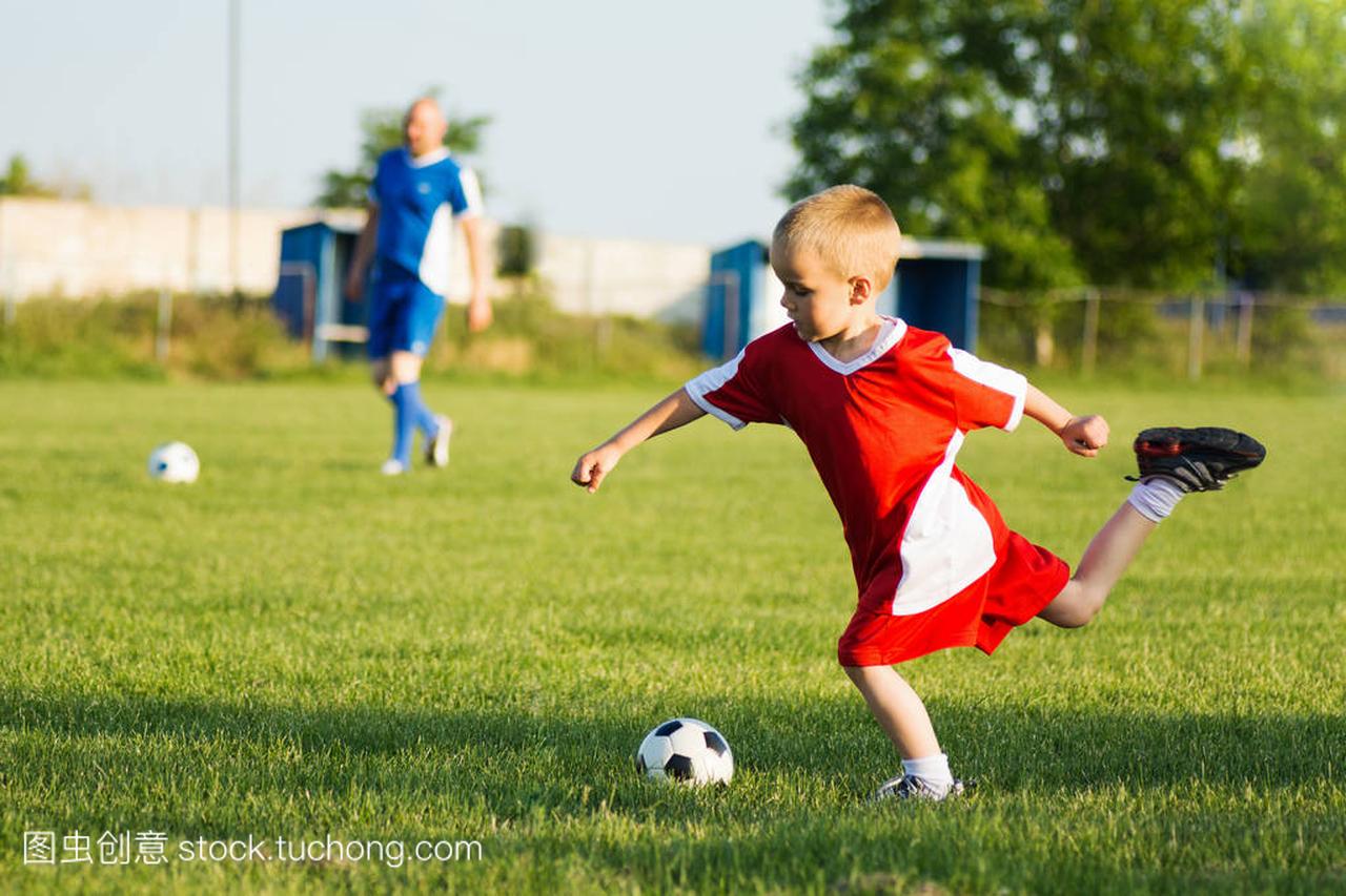 4岁的男孩在足球场上射击足球运动训练户外比