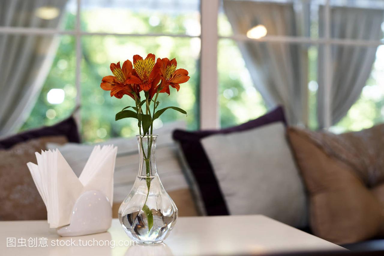 玻璃花瓶里的新鲜百合花, 在窗边的软枕头背景