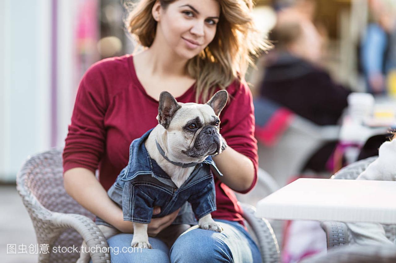 olding adorable fawn french bulldog in her lap in