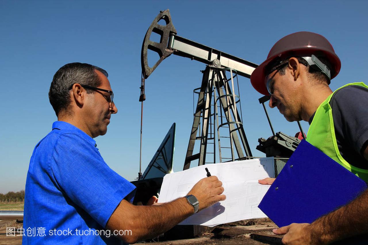 石油工程师与笔记本电脑和蓝图在油田管理与勘
