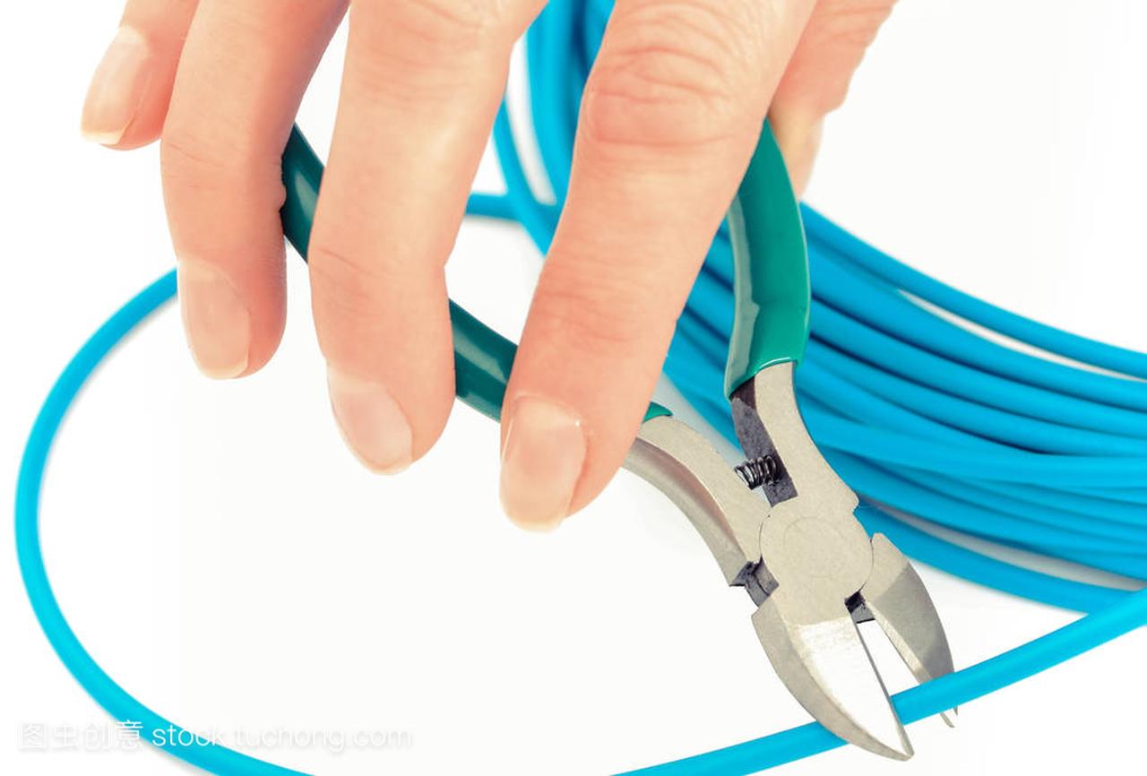 Hand with metal nippers is cutting blue cable fo