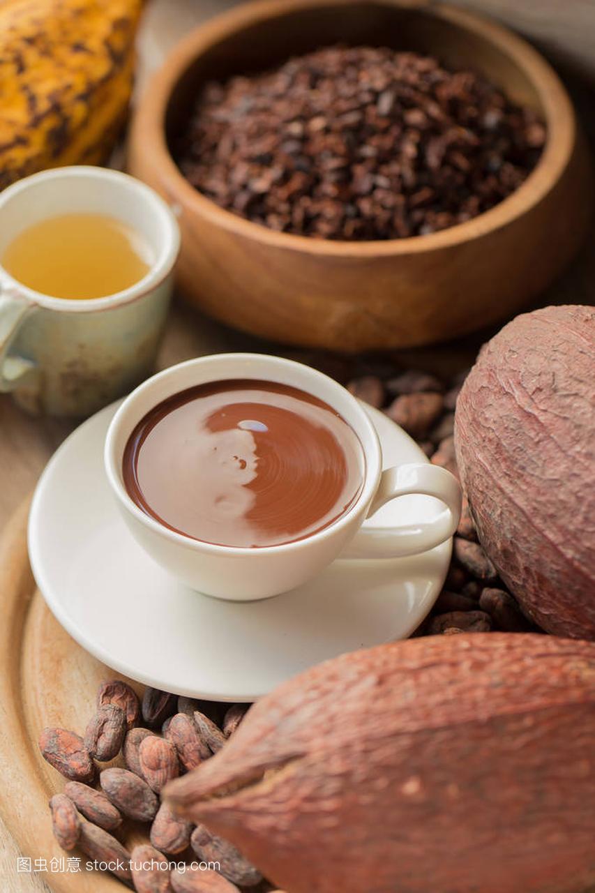 Fresh chocolate beverage with tea and cocoa fruits on table.