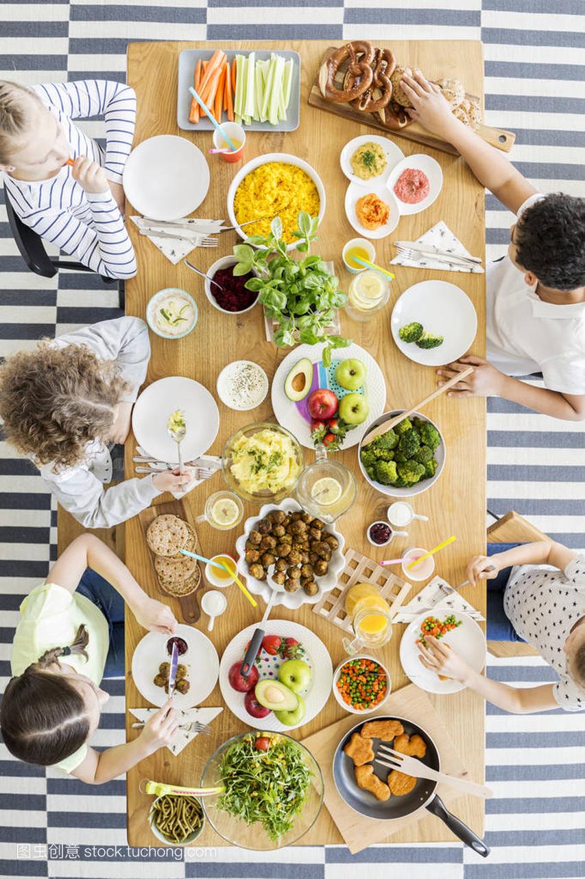 Top view on children eating dinner during birthday party at home