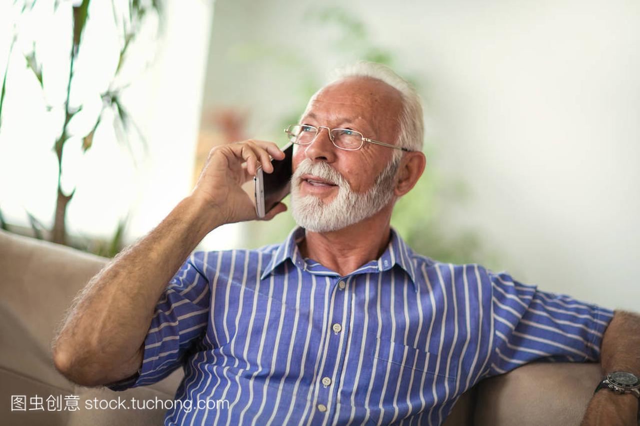 Senior man chatting on smartphone in living room