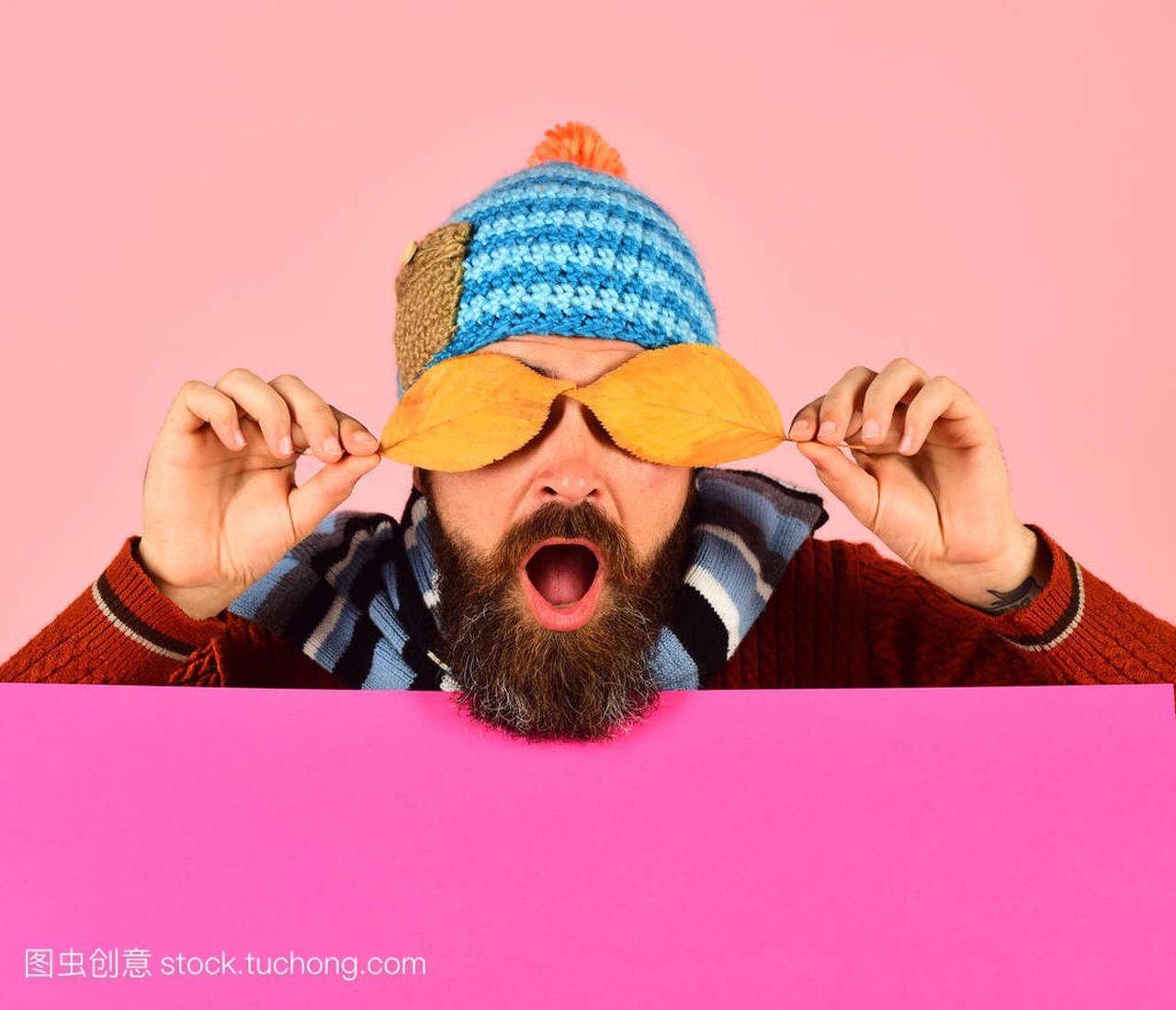 Guy with surprised face wears warm hat on pink