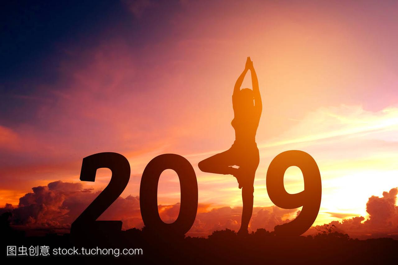剪影年轻妇女练习瑜伽在2019新年