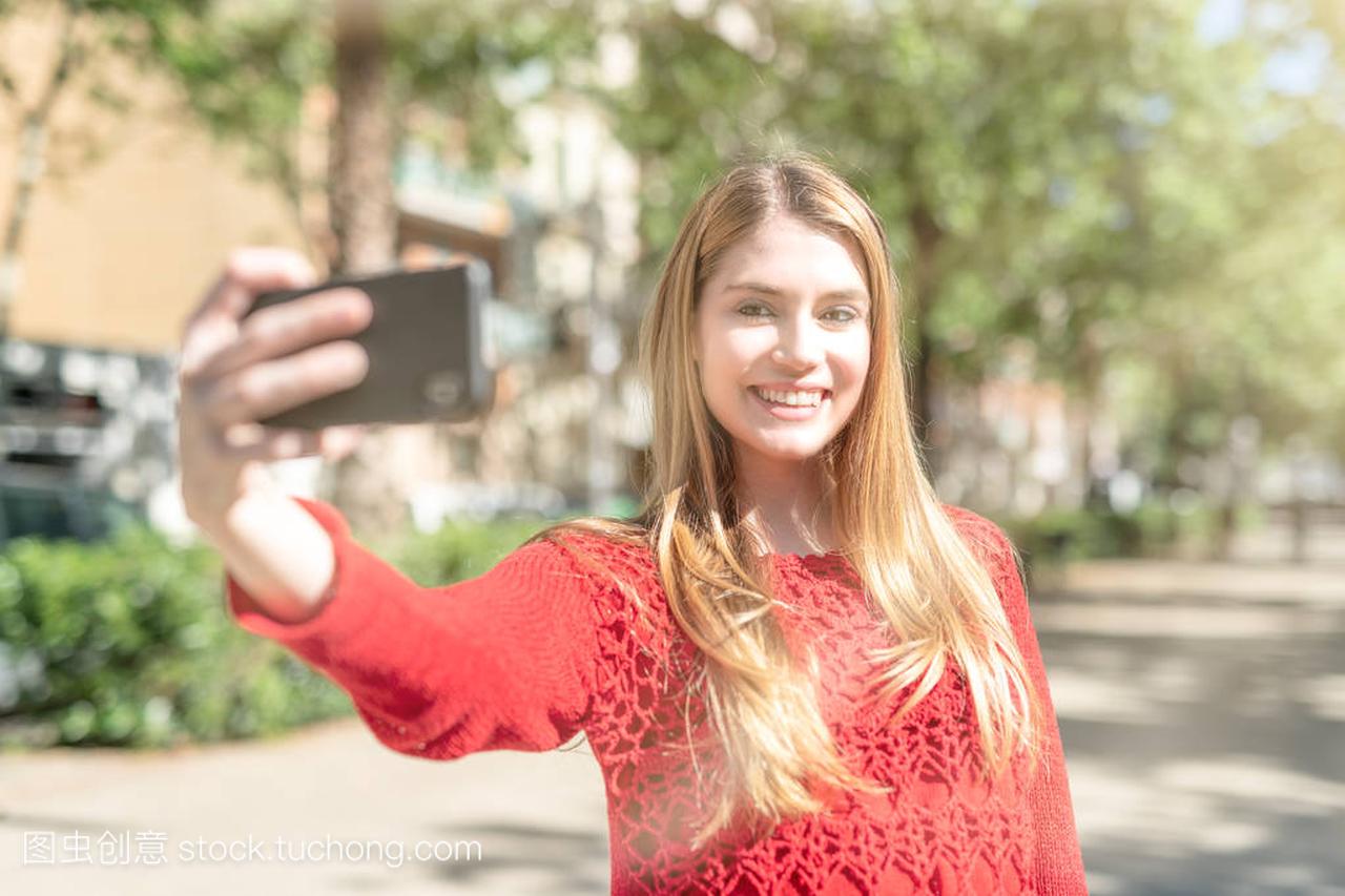 Blonde girl making selfie visiting city, sun 