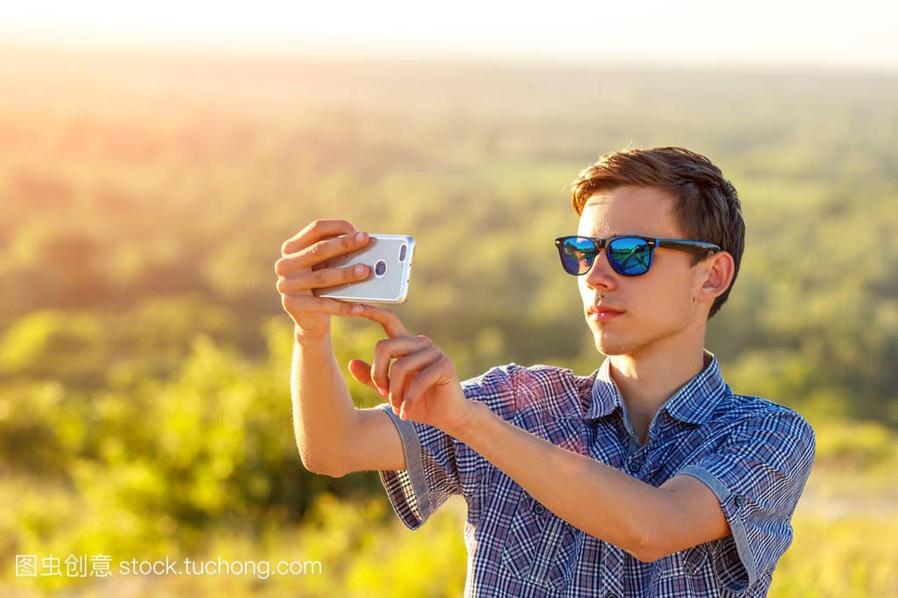 cute guy takes a selfie on the phone in the sun
