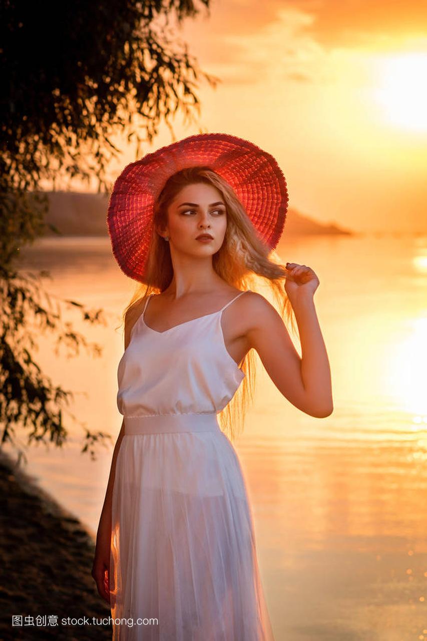 Young girl in a white dress and an red hat stand