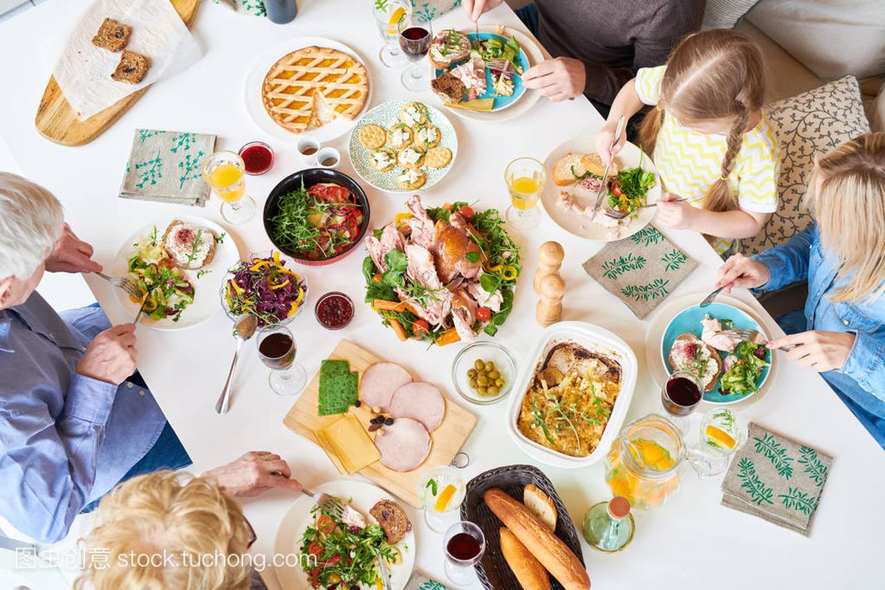Directly above view of big happy family sitting at dinner table enjoying delicious homemade food during celebration