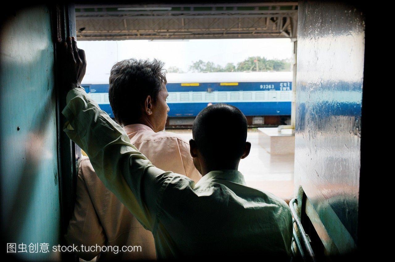 印度两个人在一列火车里,看着另一列火车通过