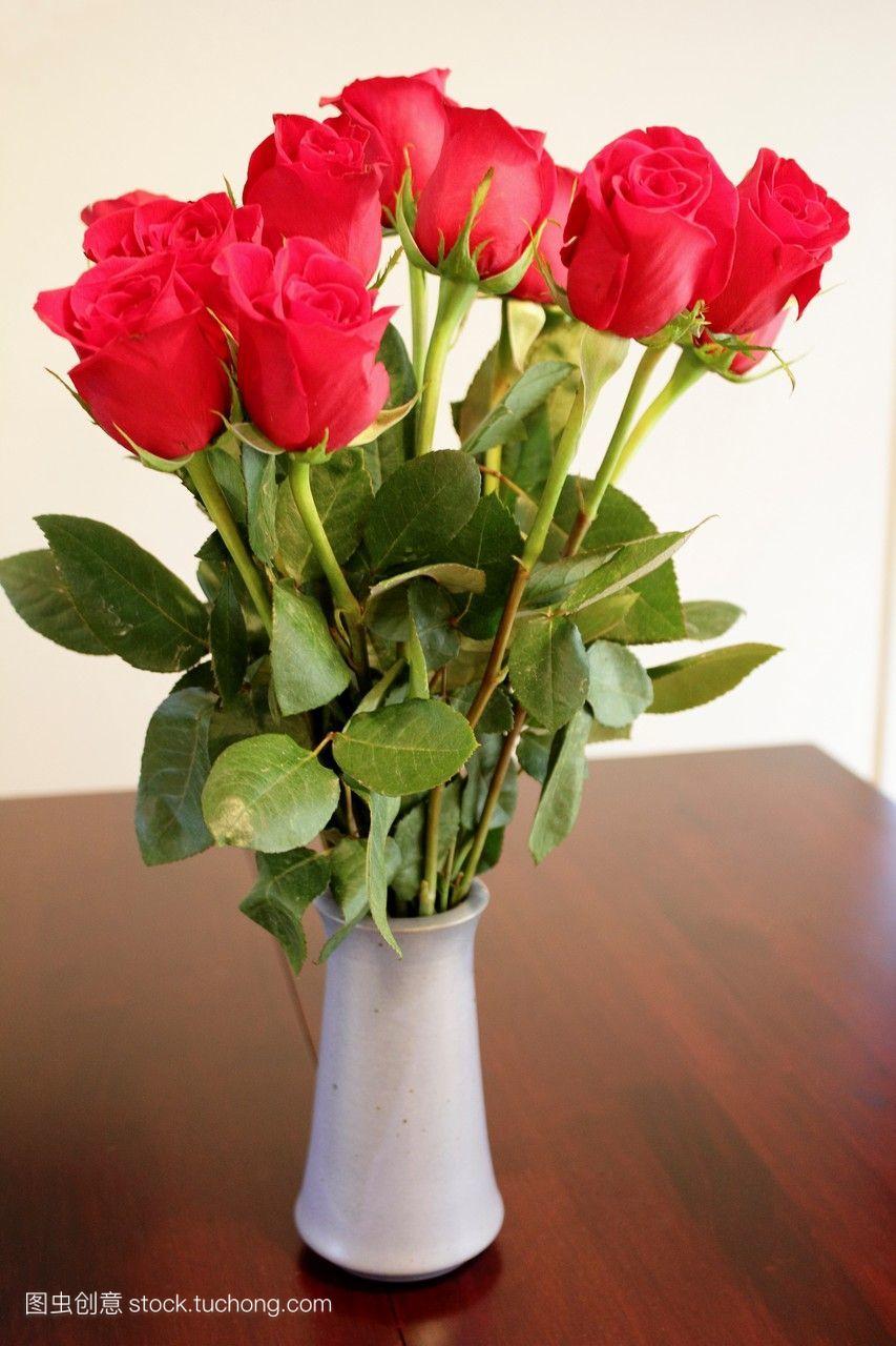 一束长柄红玫瑰在桌子上的花瓶里