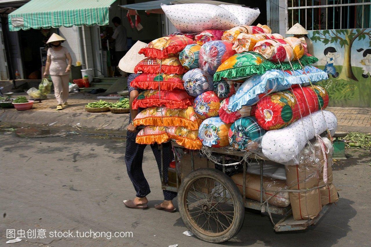 在越南胡志明市,妇女拉着装满货物和软家具的