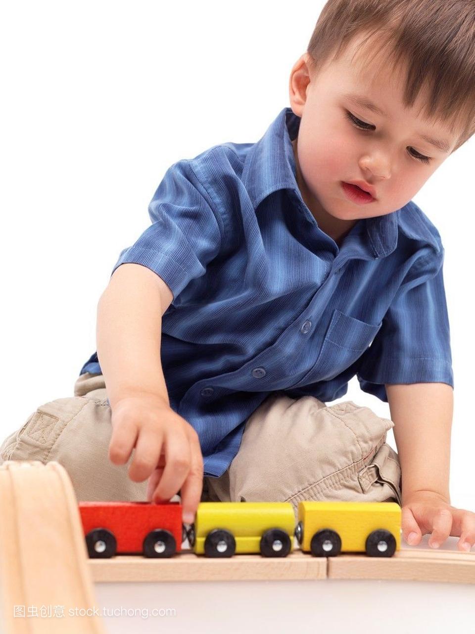 两岁的男孩在铁路上用木制玩具火车玩
