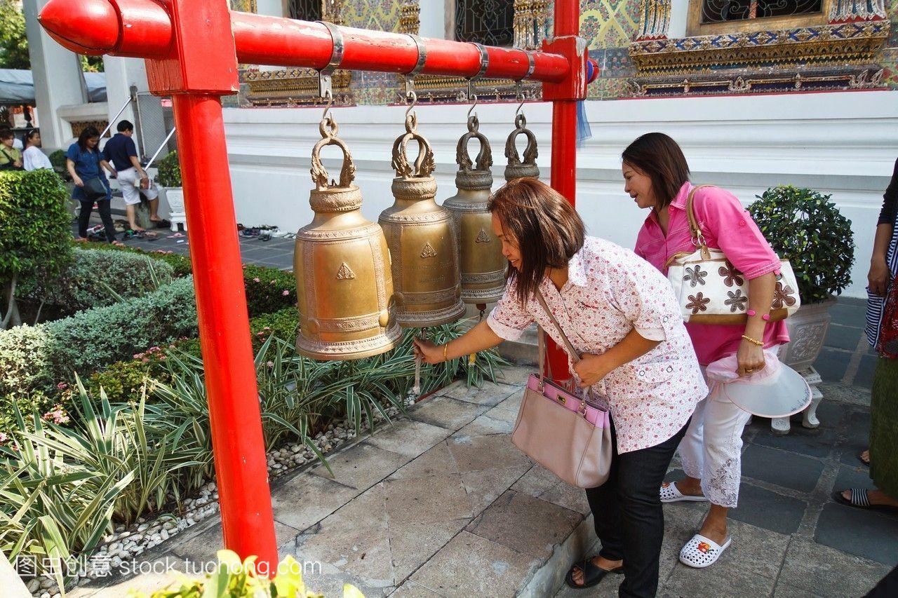 泰国曼谷,佛教信徒在庙里敲钟