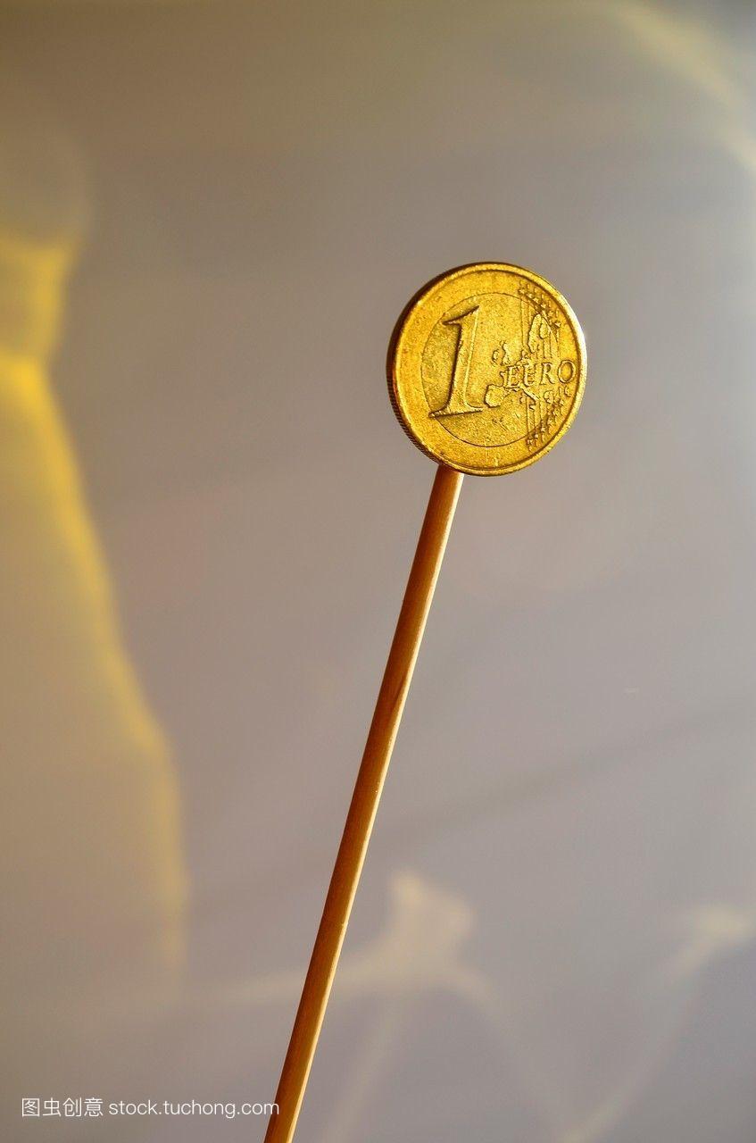 一欧元硬币像棒棒糖一样,在灰色的背景上被孤
