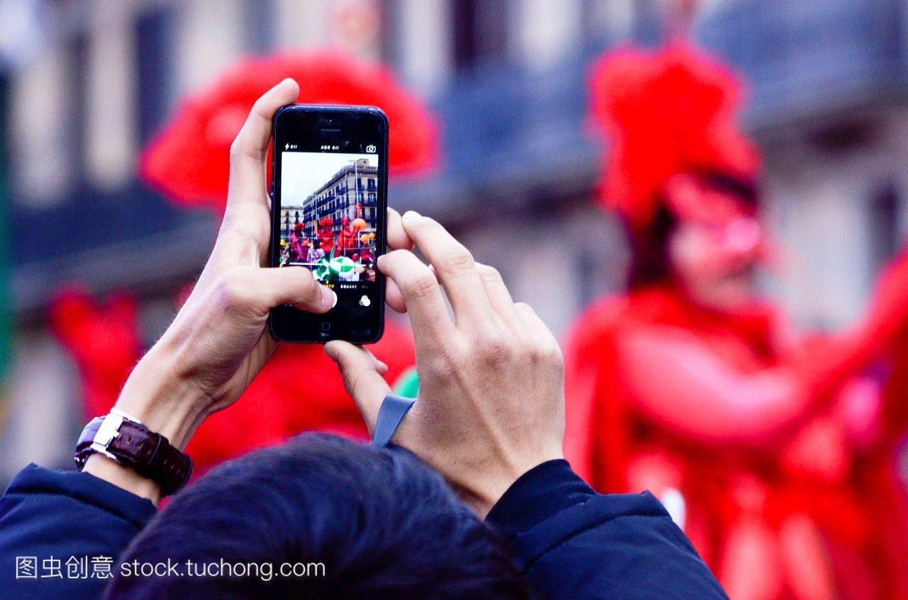 两只手拿着手机,在狂欢节上拍了一张照片。不