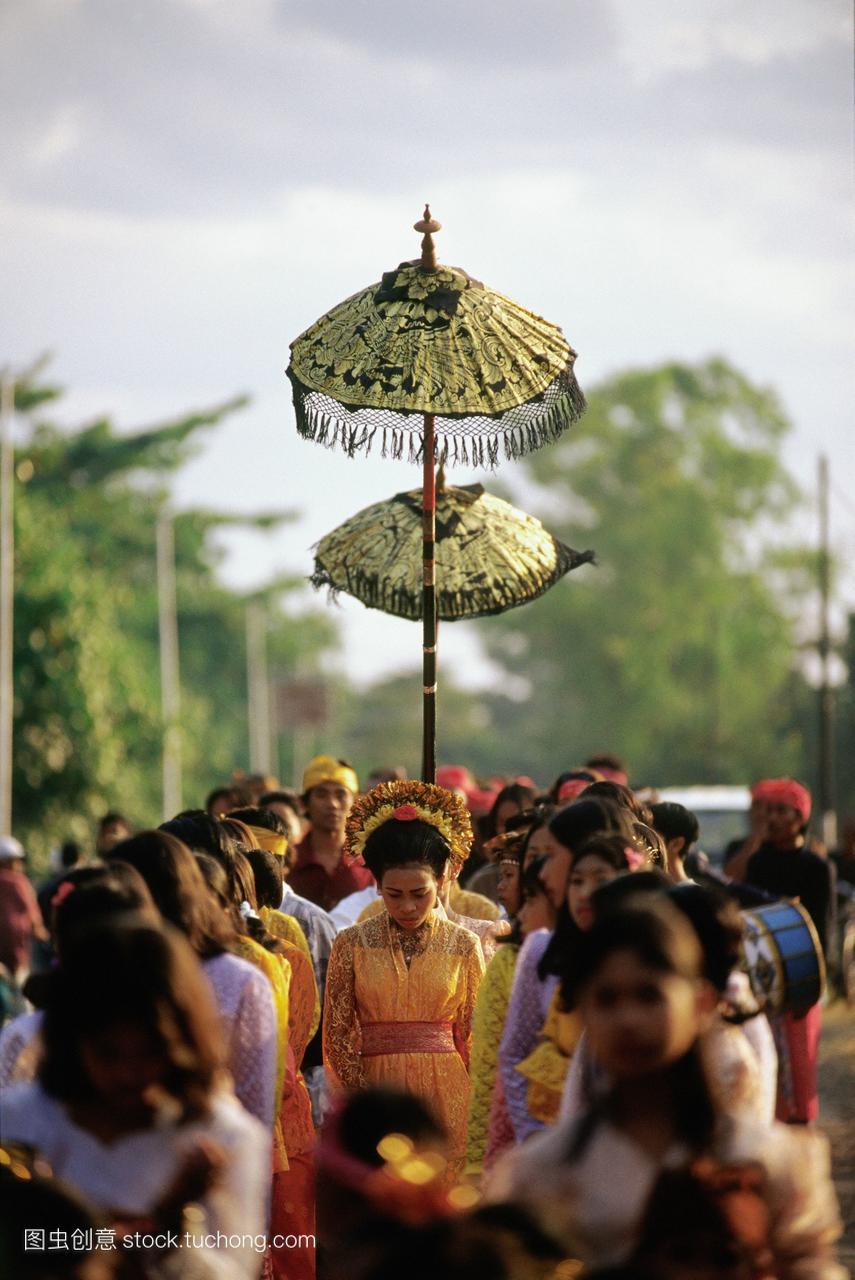 印度尼西亚龙目岛新娘走在树冠下伴随着女服务