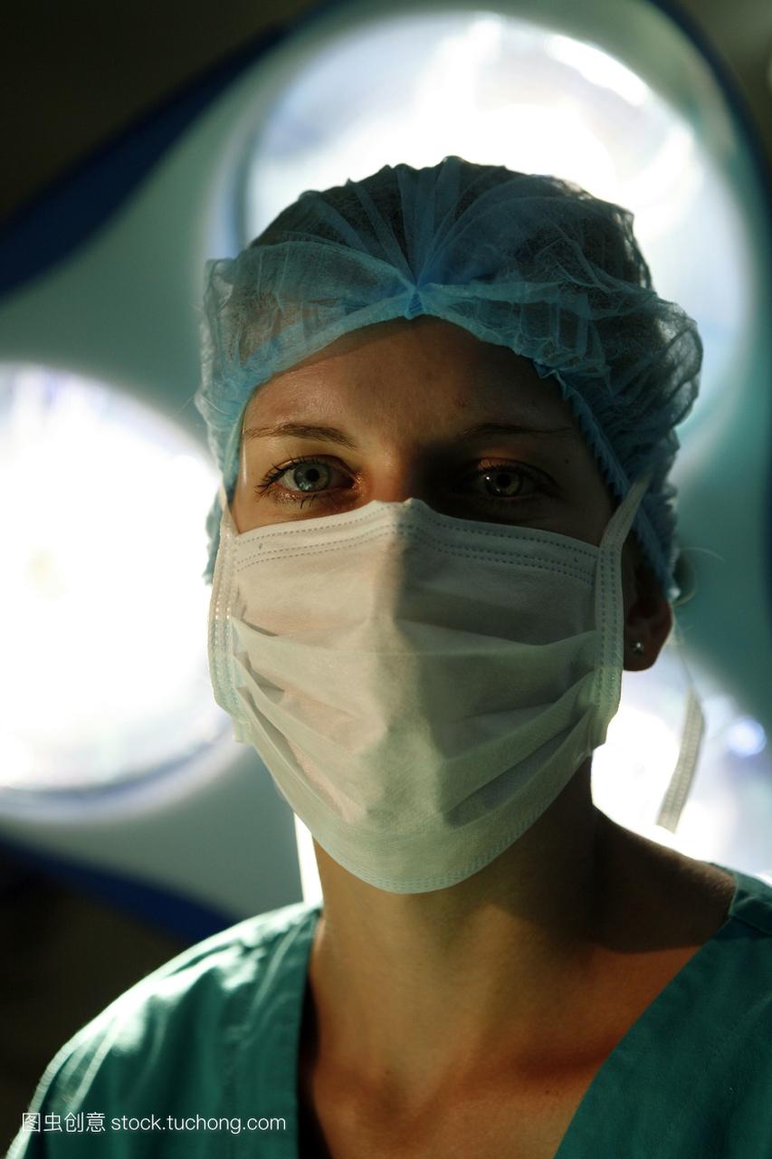 一位女外科医生从手术灯下直视镜头