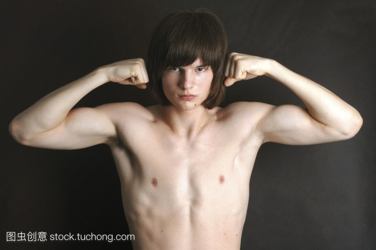 赤裸着胸部的十几岁的男孩在炫耀他的肌肉