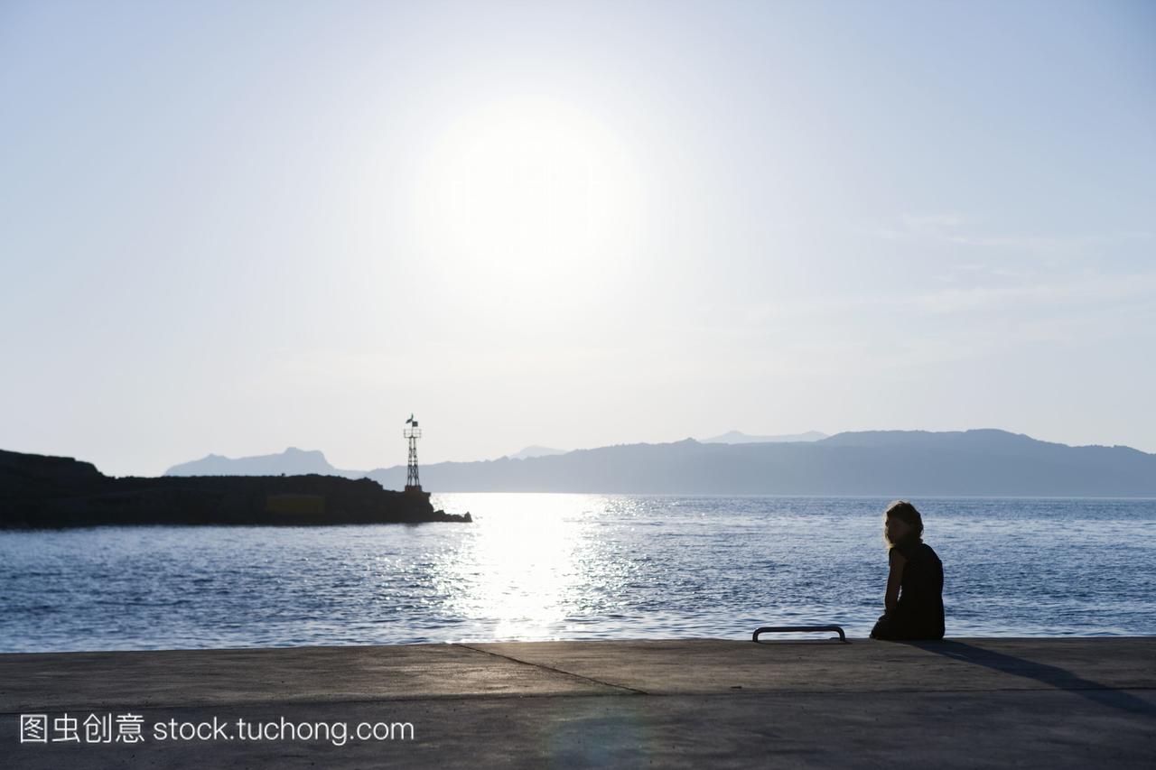 一个北欧女孩坐在希腊码头上。
