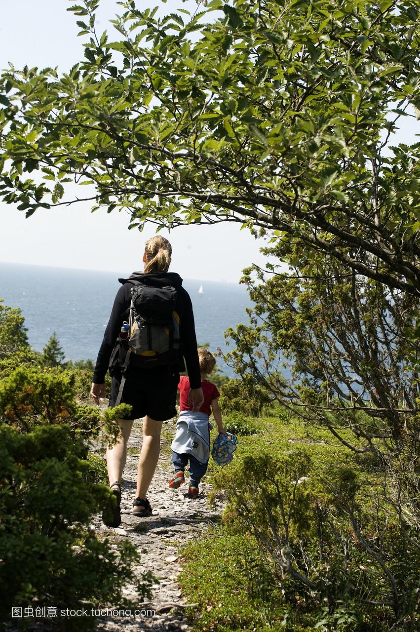 一个女人和一个男孩走向海边,瑞典。