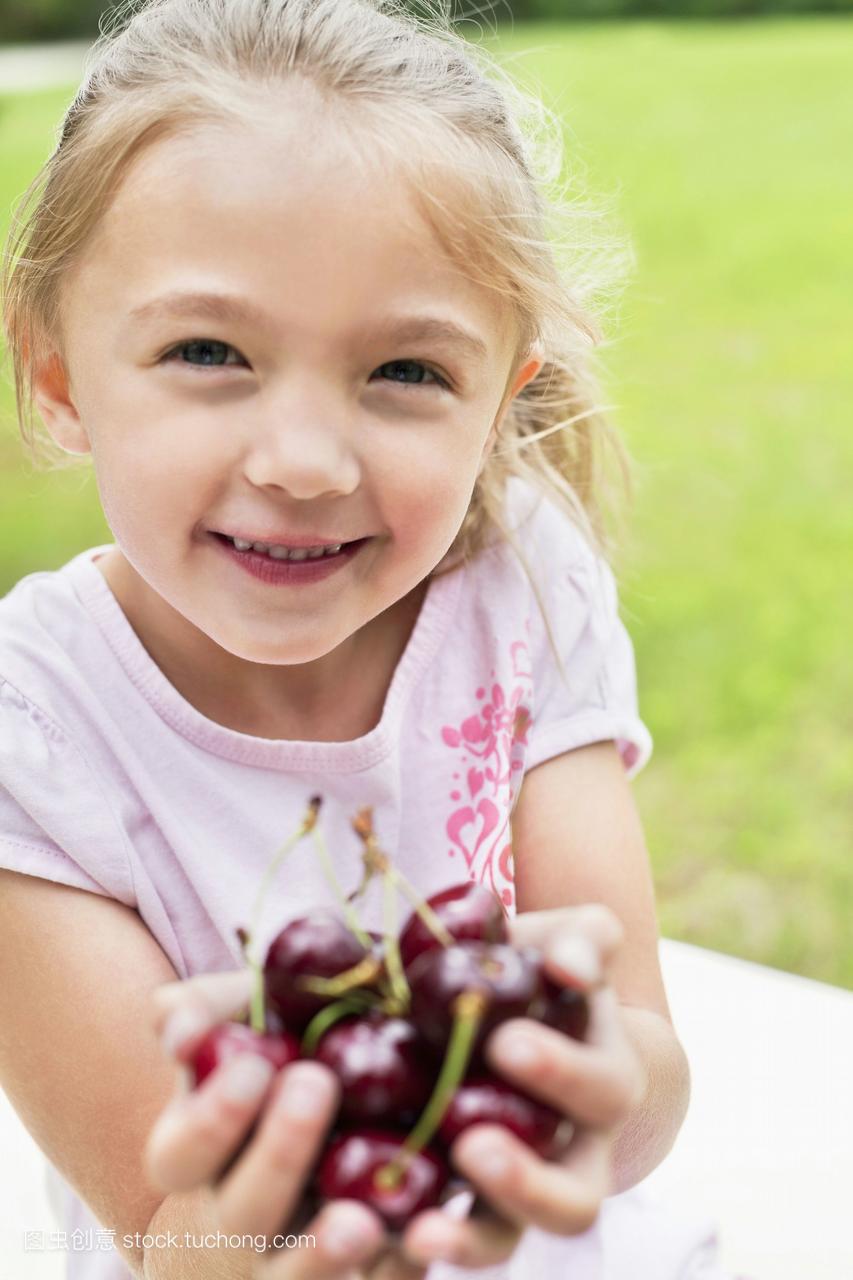 一个快乐的女孩的肖像,手满是冰樱桃
