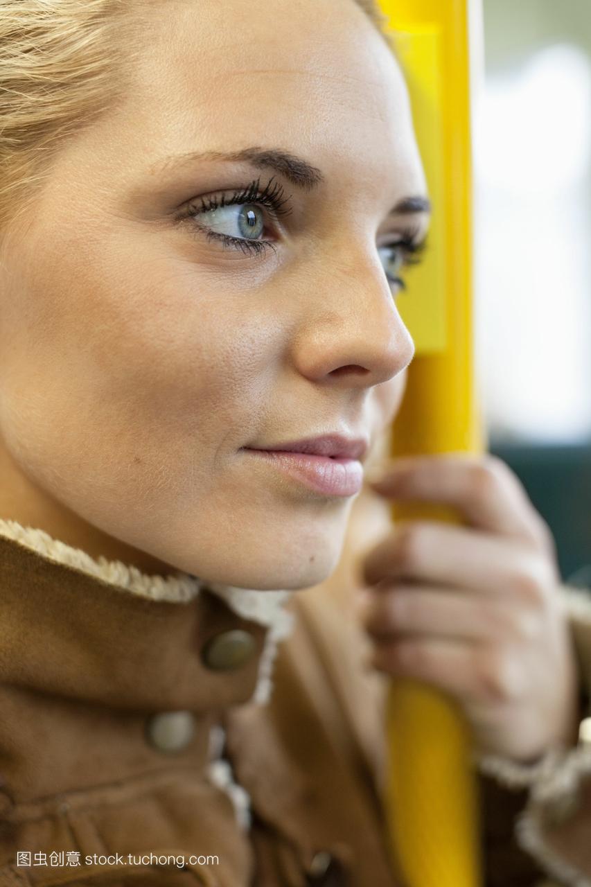 沉思的女人在公共汽车上抱着栏杆