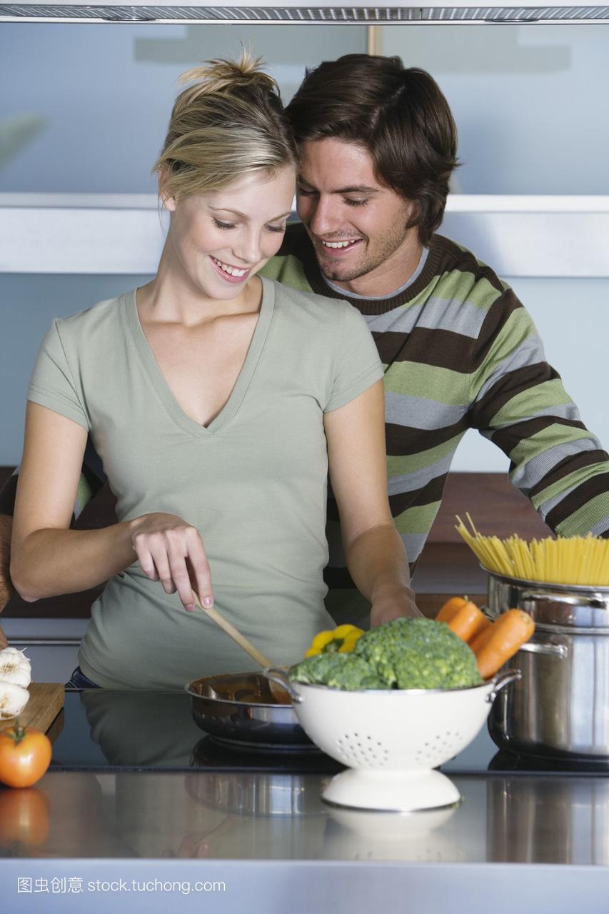 现代厨房里的年轻夫妇,一起做饭,拥抱,微笑