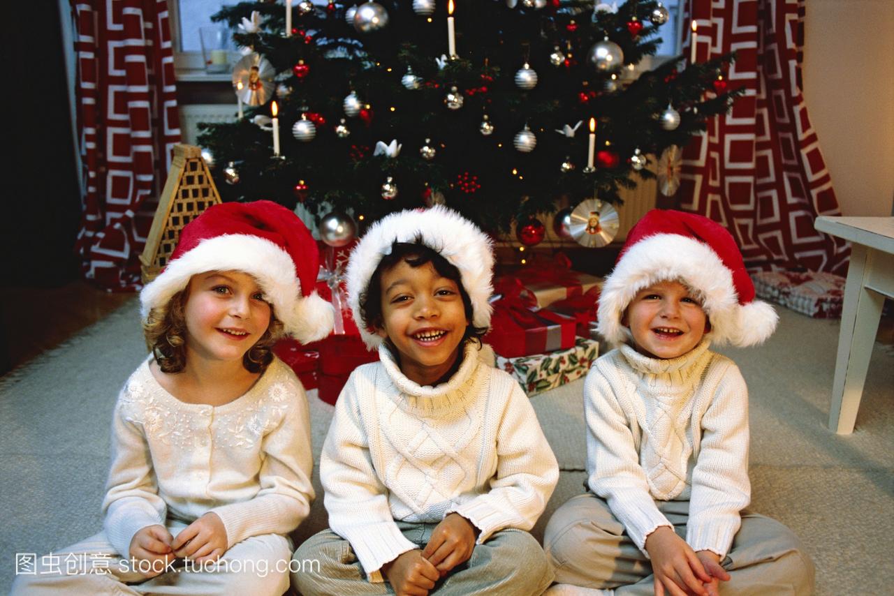三个小孩在圣诞老人的画像和睡衣等待圣诞老人