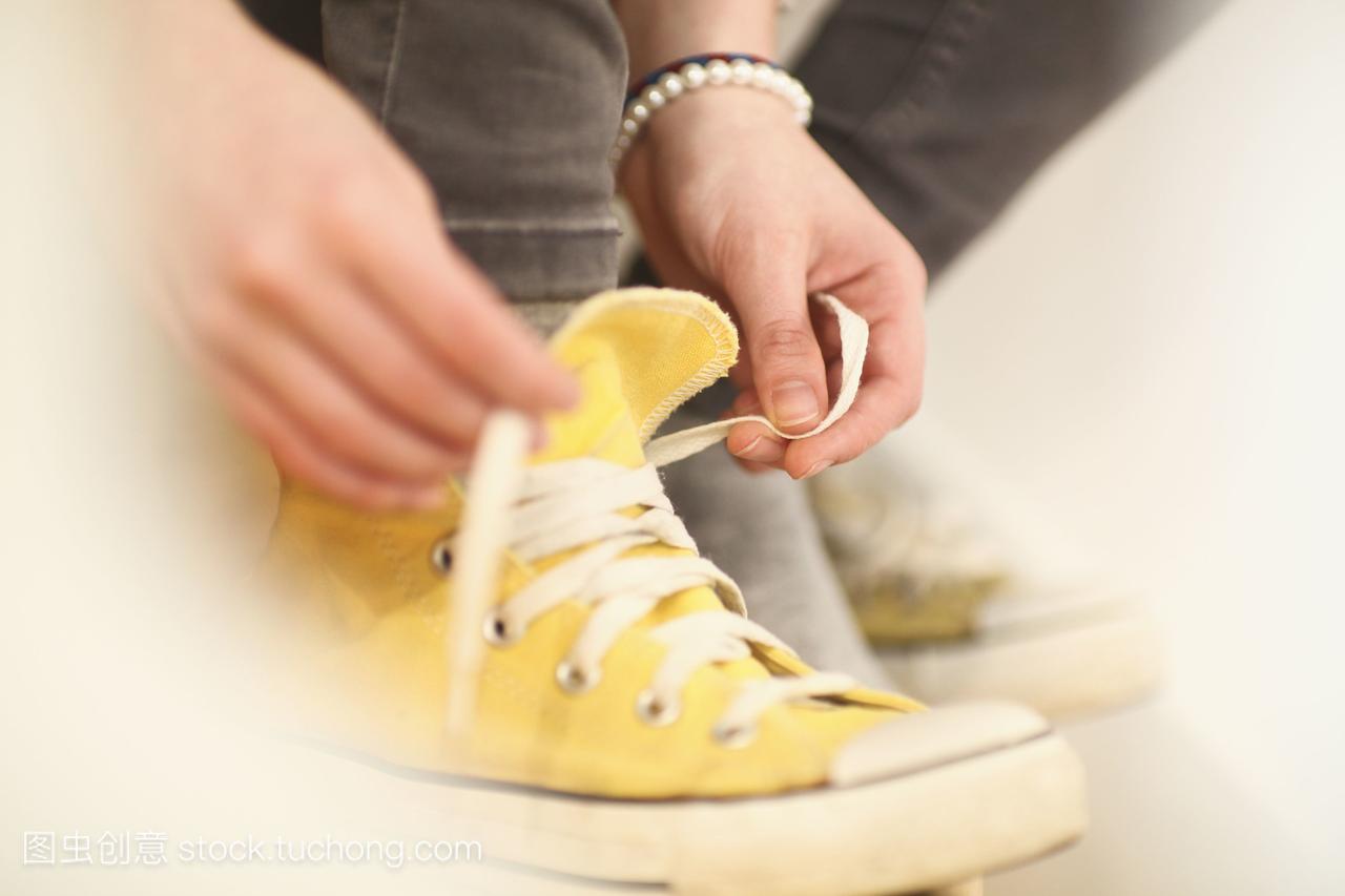 近十几岁的女孩把鞋带系在运动鞋上