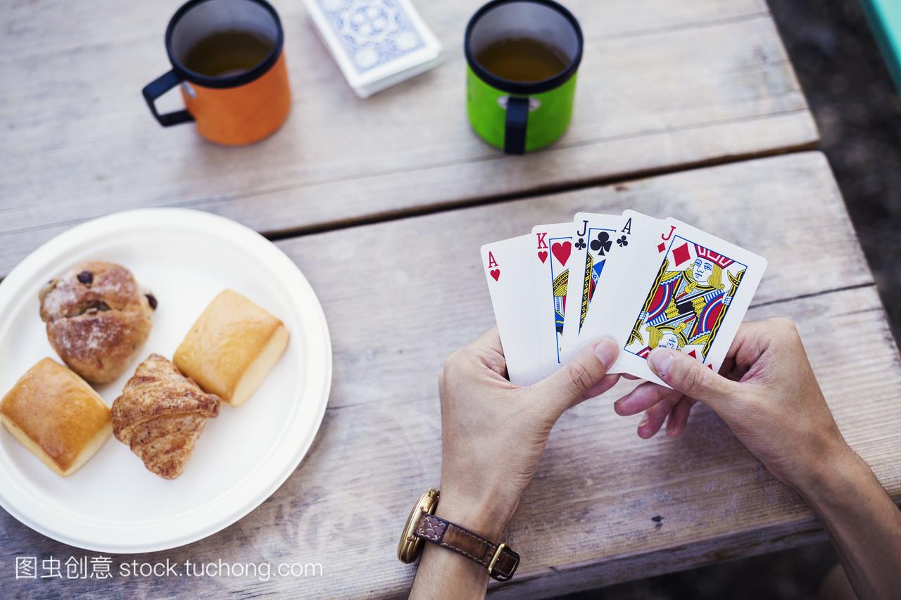一个人坐在桌旁,手里拿着扑克牌。