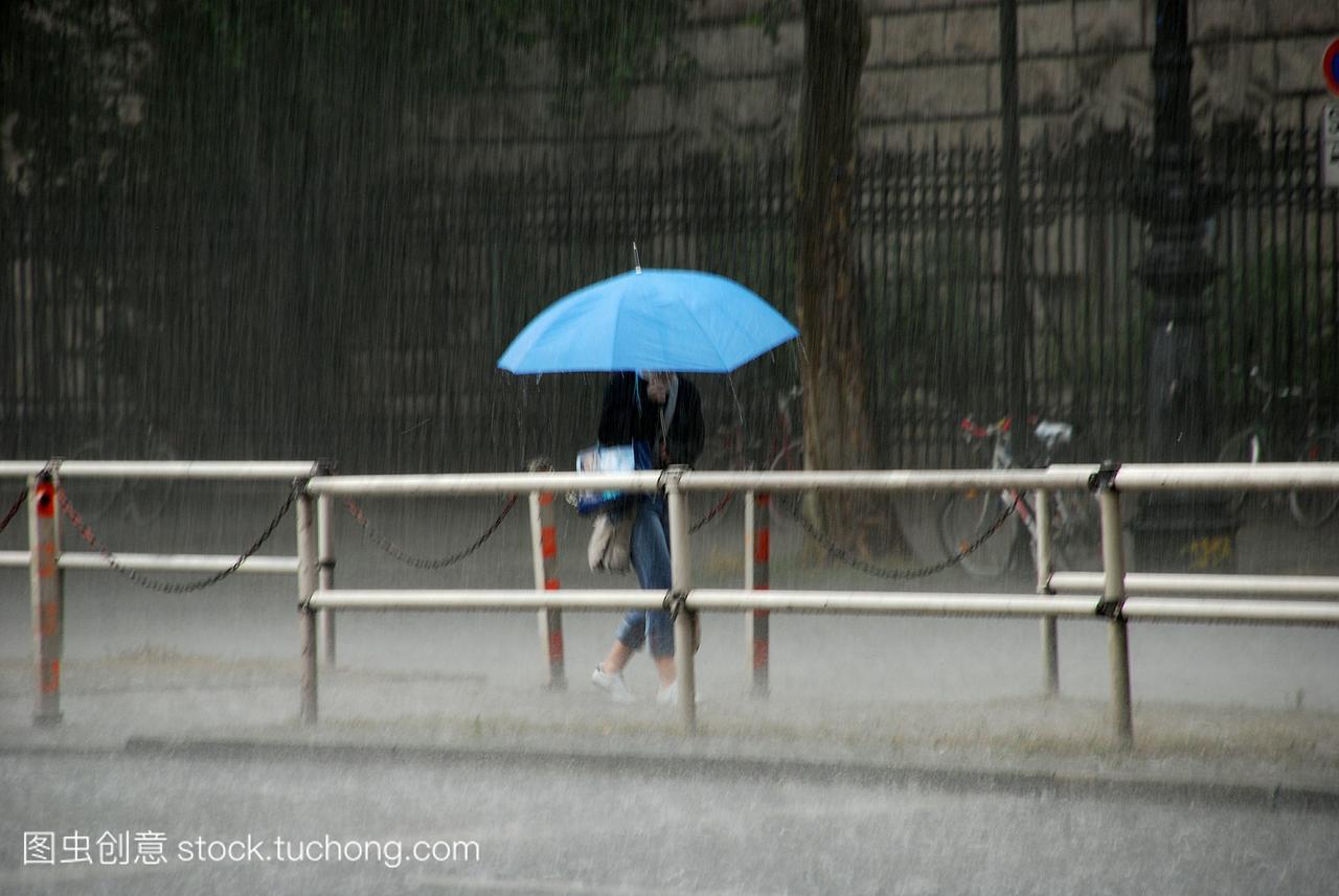 带着蓝色雨伞的女人冒着大雨