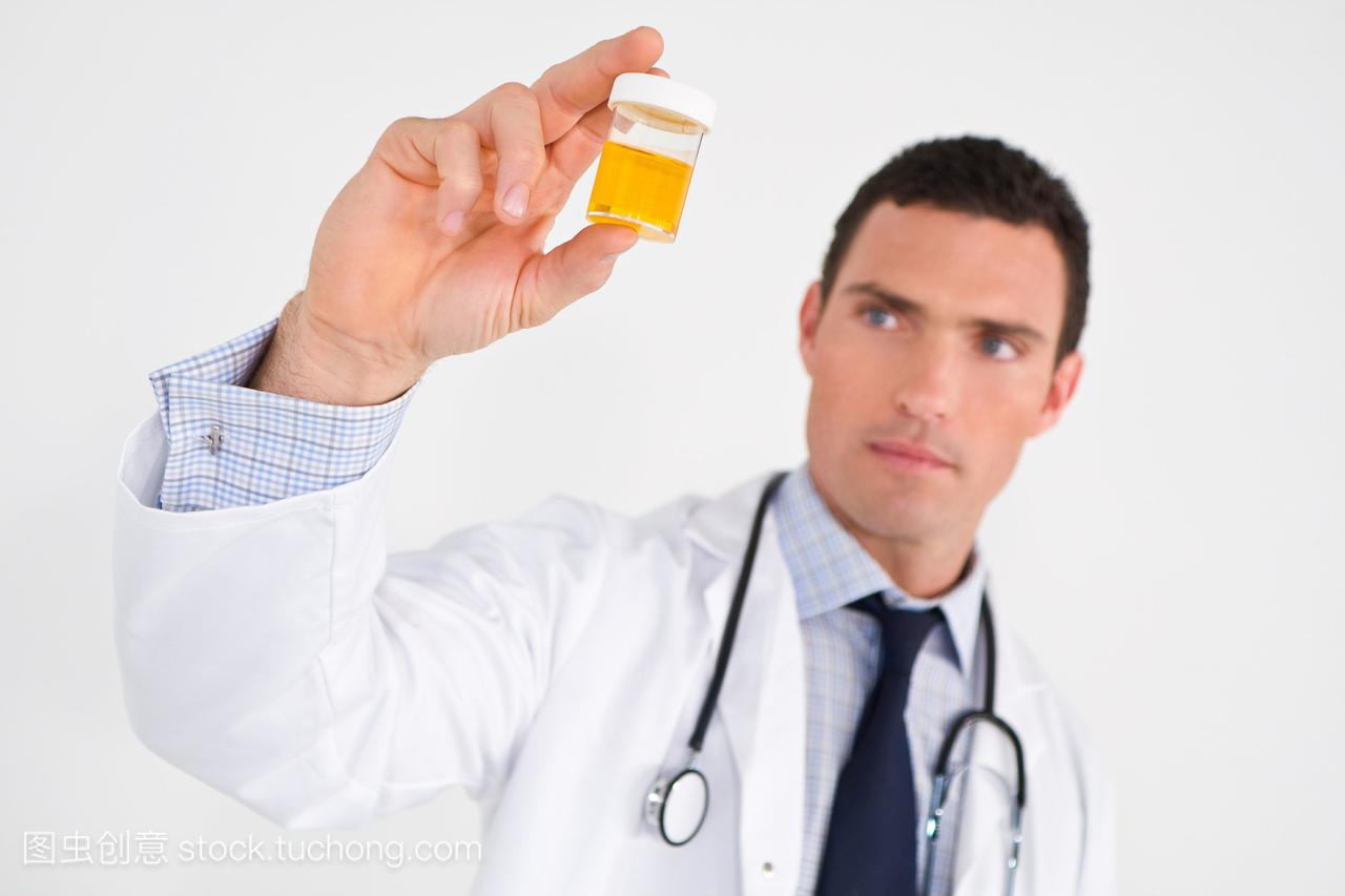 一位男性医生检查尿液样本。重点放在样品瓶上