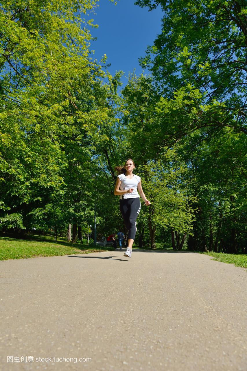 漂亮的女人在夏日公园慢跑。女性在户外运动健