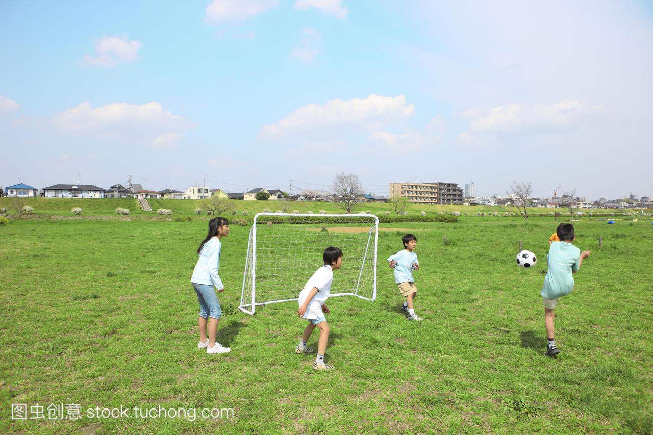四个孩子在球门附近踢足球。futako-tamagawa