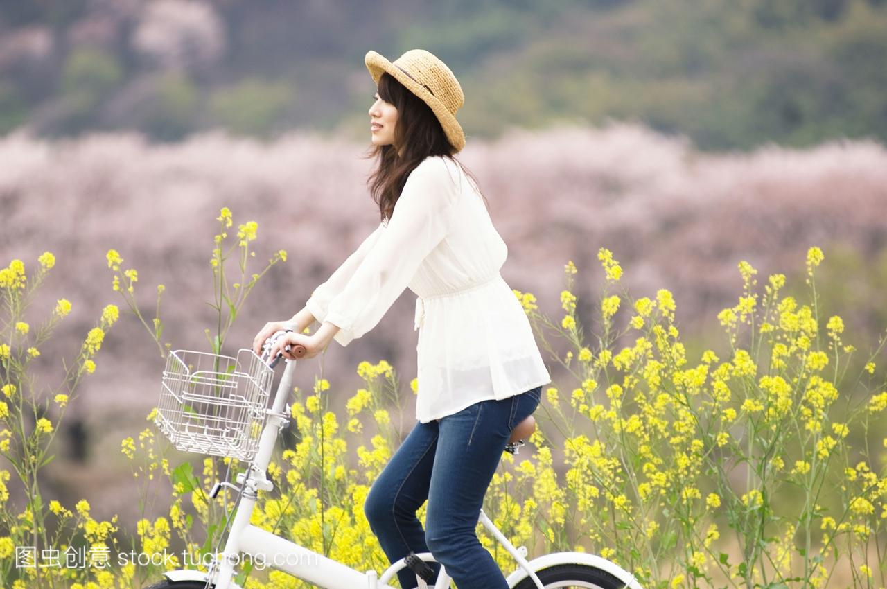 女人骑自行车通过春天的风景