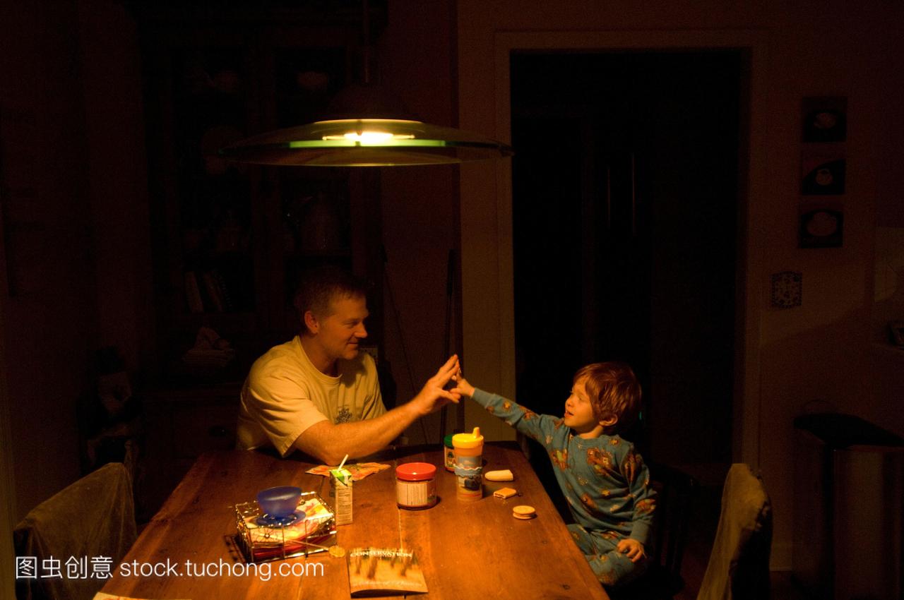 一个3岁的男孩与他的父亲分享零食。