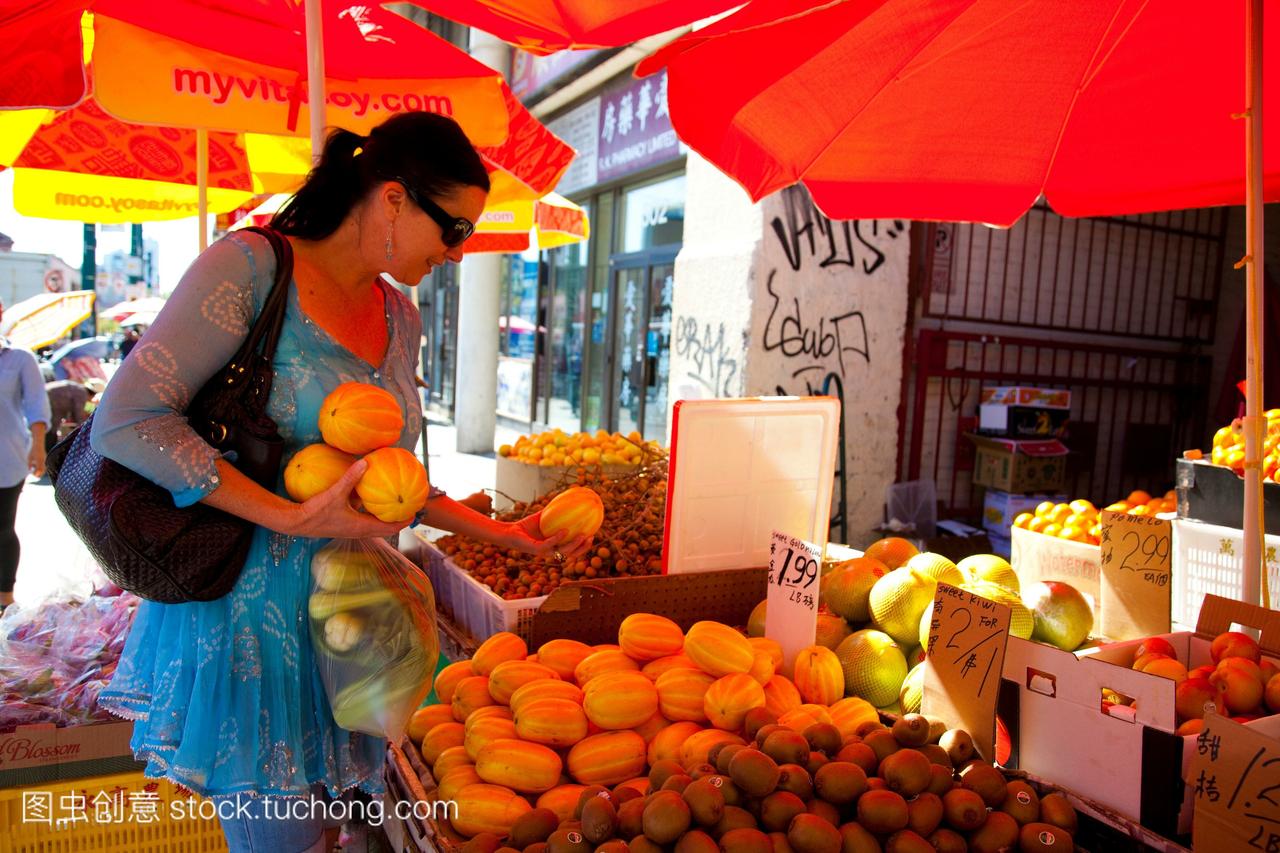 一位购物者从多伦多唐人街的露天市场挑选水果