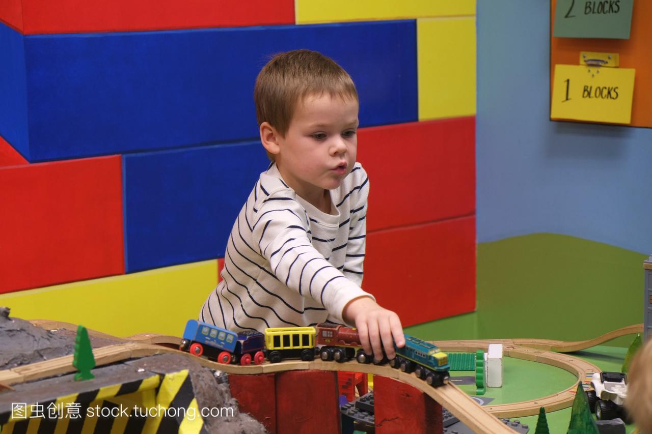 一个四岁的男孩在室内玩耍中心玩玩具火车。