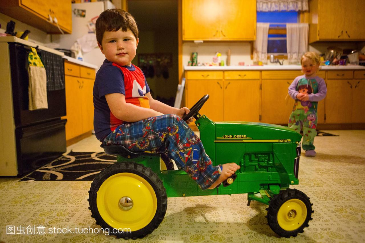 一个超重的4岁男孩骑着玩具拖拉机。