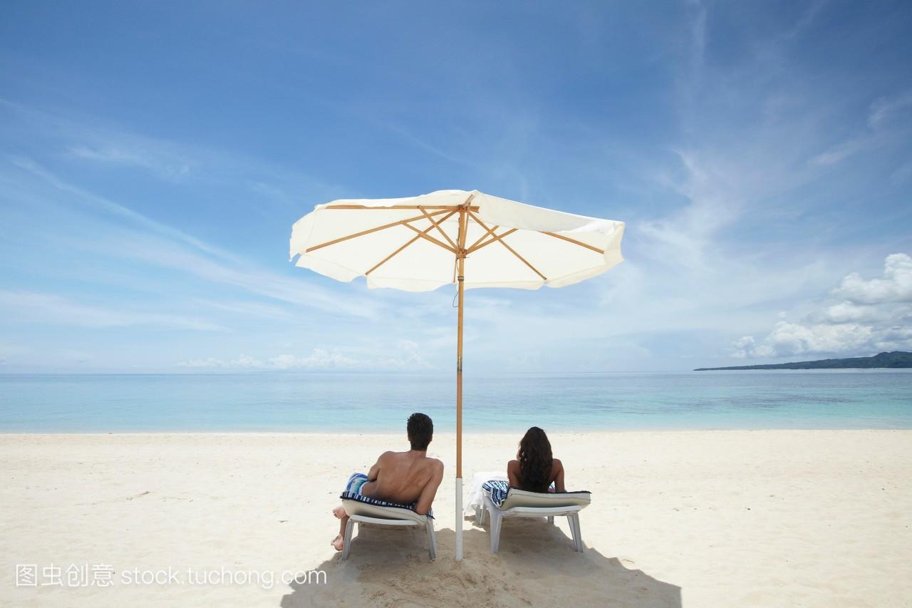 一对夫妇在沙滩上晒太阳。