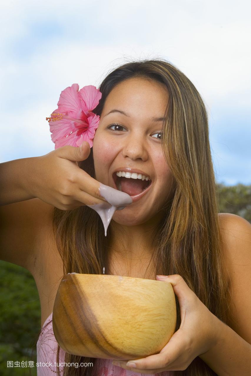 夏威夷,女孩用手指从木碗里吃着poi。
