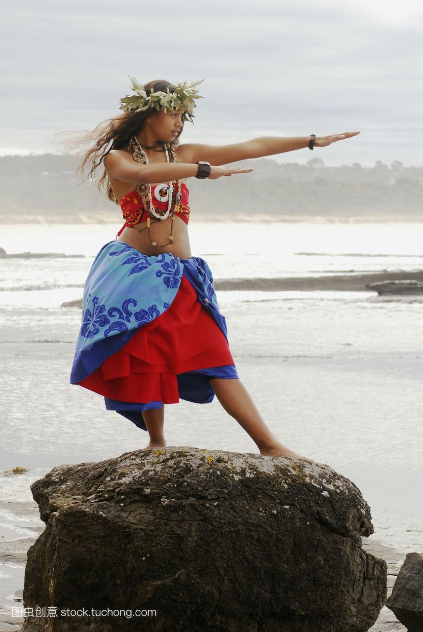 美丽的夏威夷女孩在俯瞰大海的岩石上跳舞。