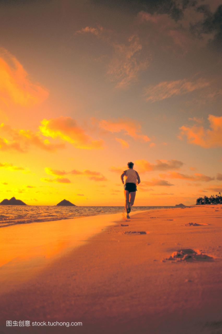 视图从后面人沿着海岸线日出粉橘色的天空