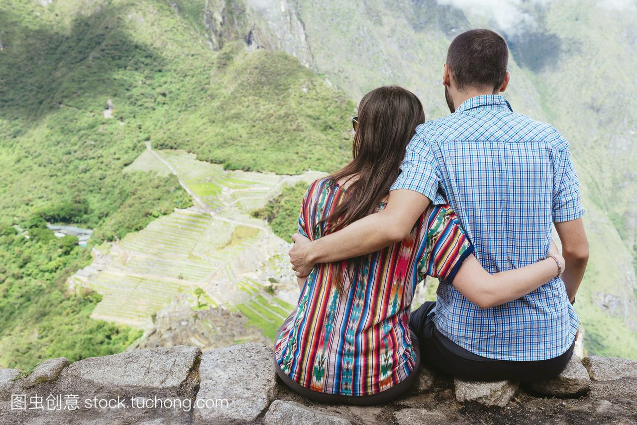 秘鲁,一对夫妇坐在那里欣赏马丘比丘城堡的景色