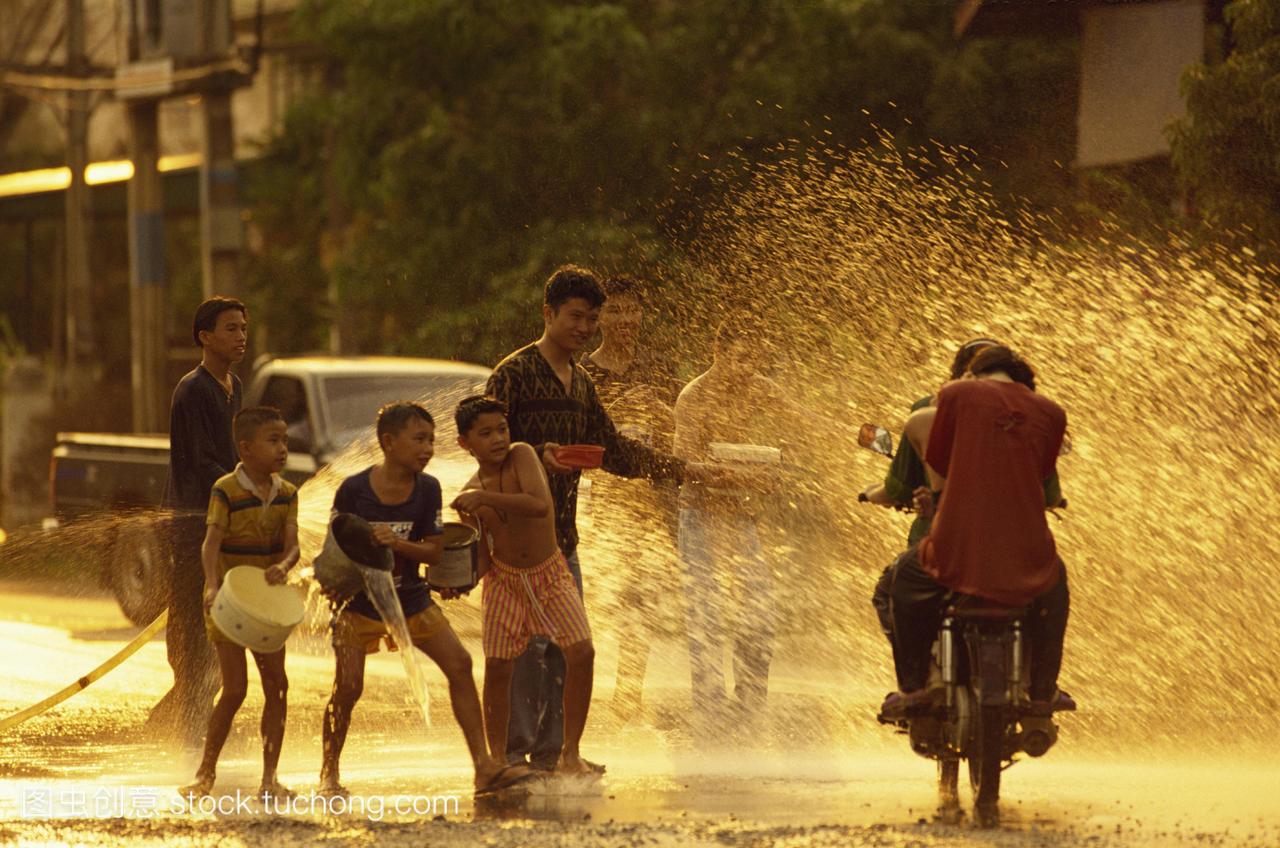 骑摩托车的人被男人和男孩用水洗澡Songklan