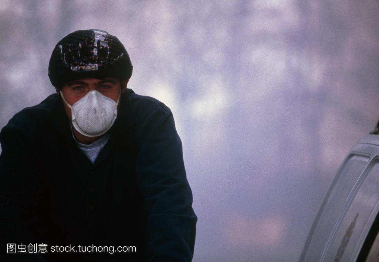 空气污染空气污染骑车人戴着面具和周期头盔面