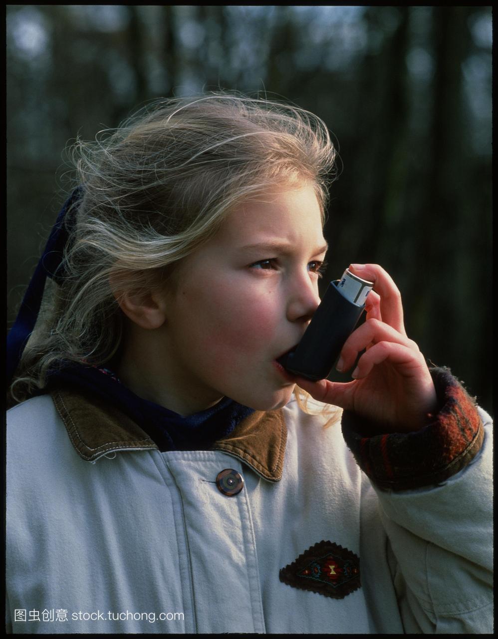 入器。年轻女孩使用气雾剂吸入器治疗支气管哮
