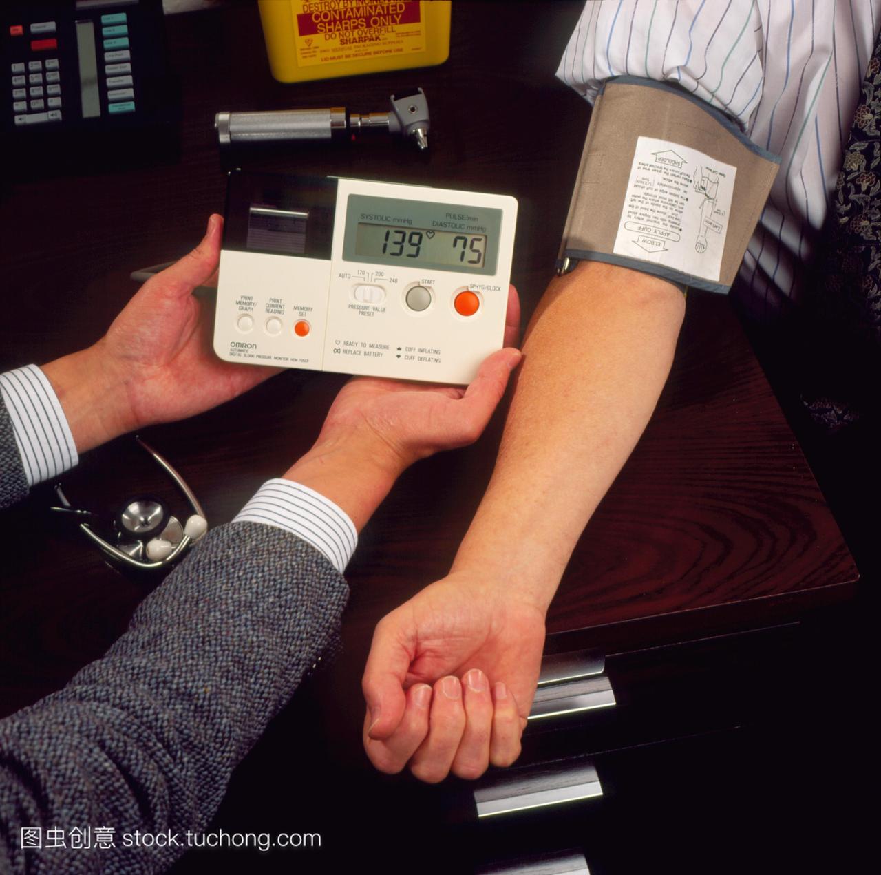 血压测量。一位普通医生的手在测量一位老人的